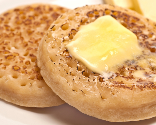 Close-up of two English muffins, one with a pat of butter melting on top.