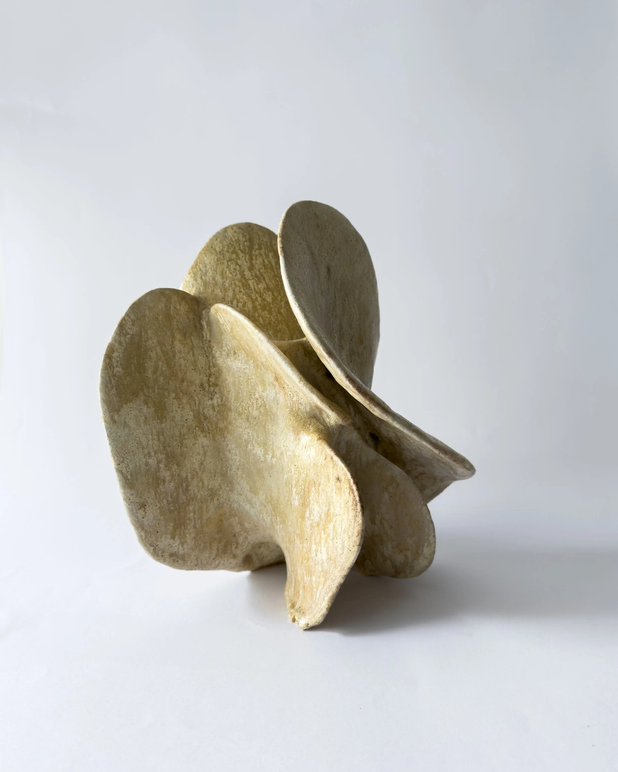 A sculpture of abstract shapes made of stone or similar material, with a smooth, weathered surface, set against a plain white background.