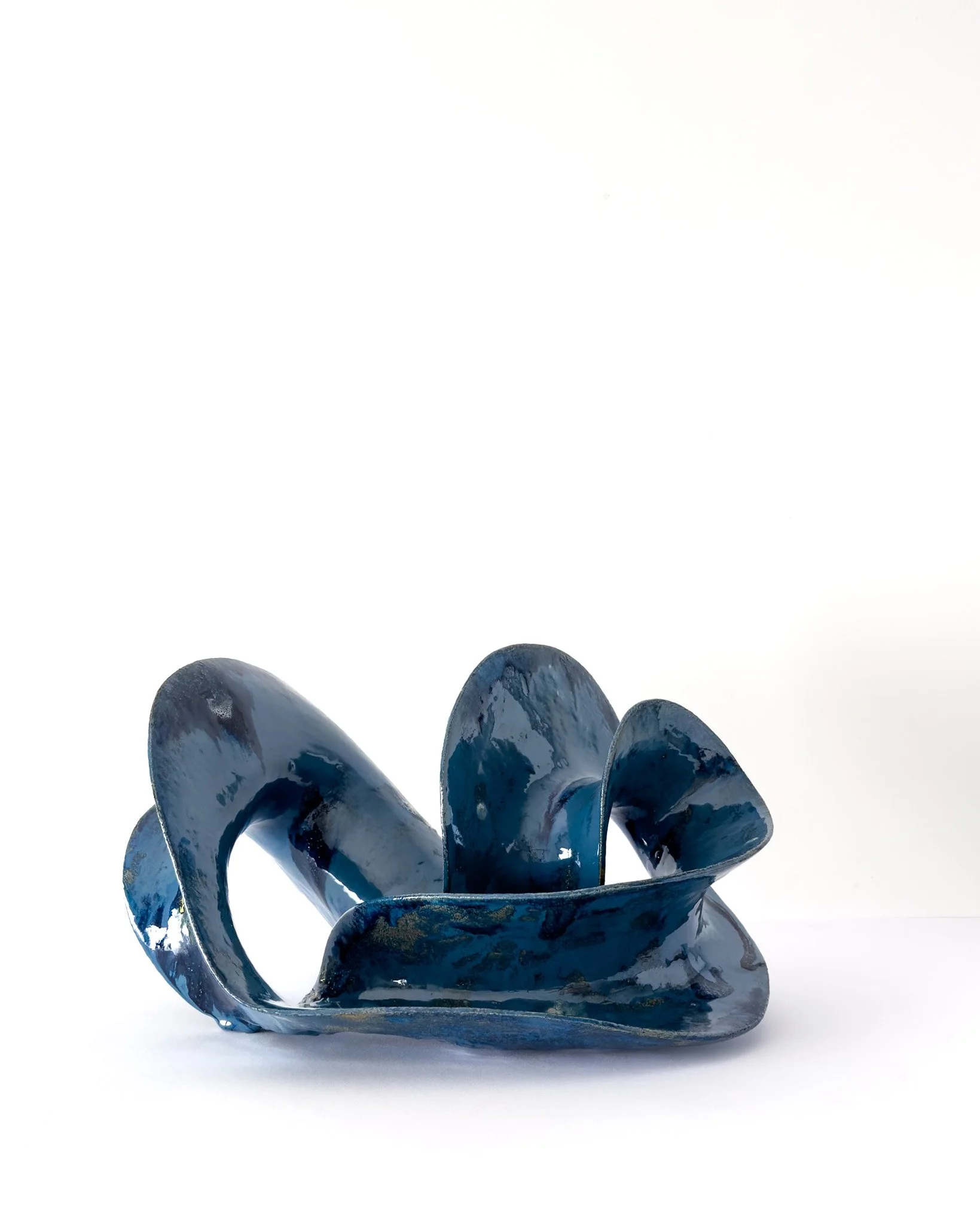 Blue abstract sculpture with flowing curved shapes, set against a plain white background.