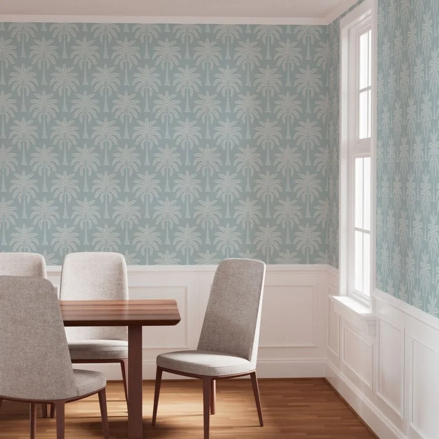 Dining room with palm tree patterned wallpaper, white wainscoting, hardwood floor, and a window with sunlight, furnished with a wooden table and four beige upholstered chairs.
