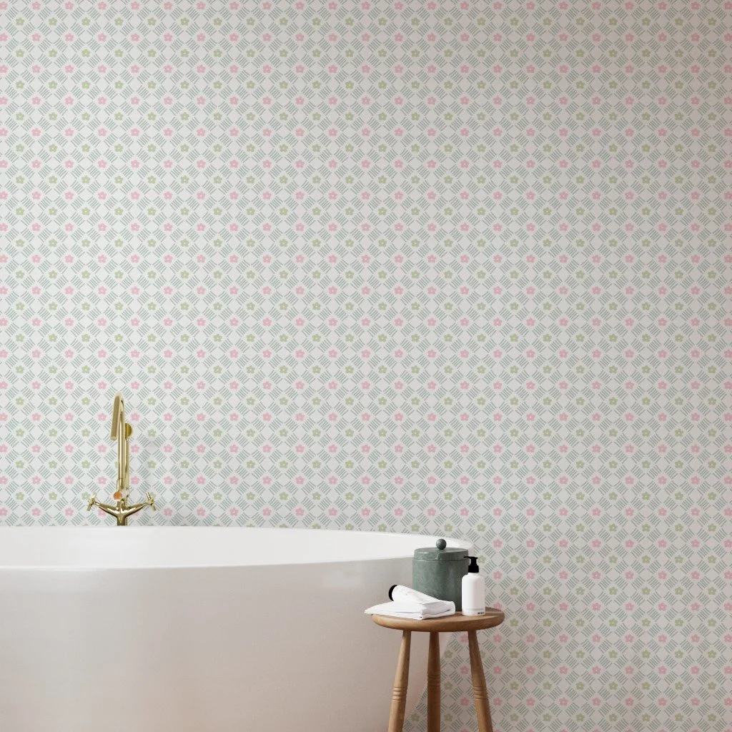 A minimalist bathroom with floral patterned wallpaper, a white bathtub with a gold faucet, and a small wooden table holding a towel, a green jar, and a white soap dispenser.
