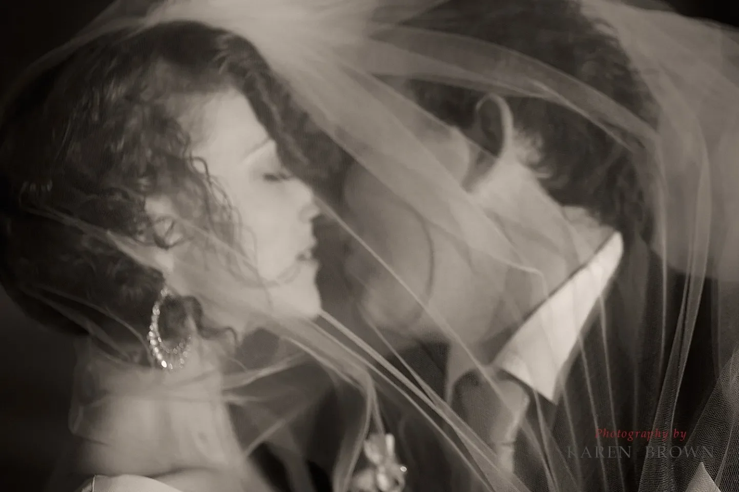 A bride and groom close together behind a veil, sharing a moment on their wedding day.