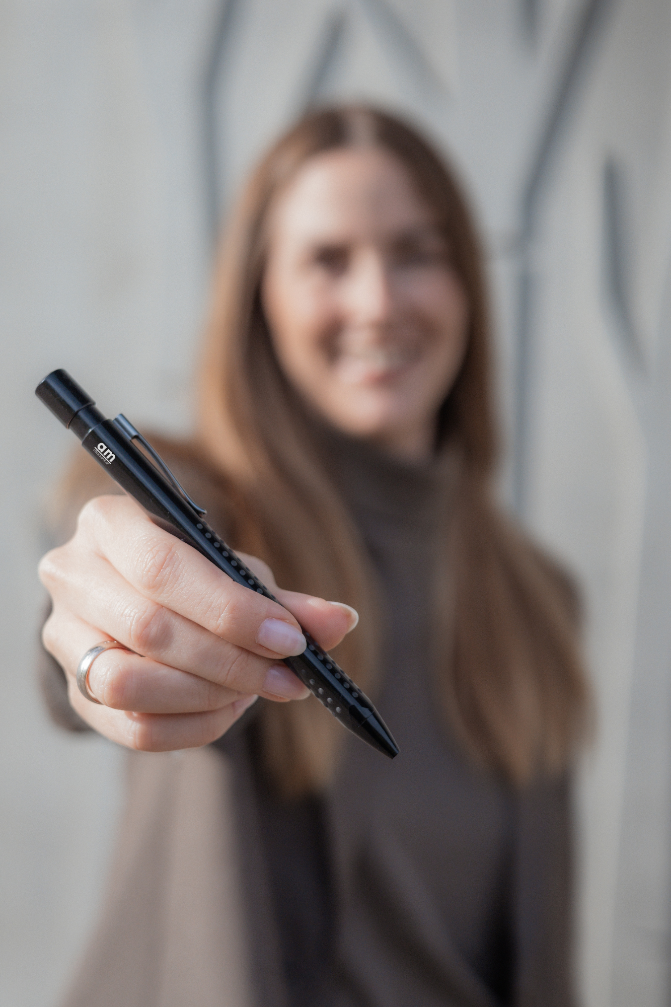 Frau mit lockigem Haar schreibt mit einem schwarzen Stift auf eine Wand.