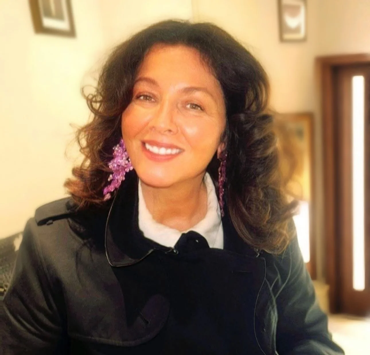 Woman in a white strapless wedding dress sitting in the back of a vehicle with a bouquet of red roses.