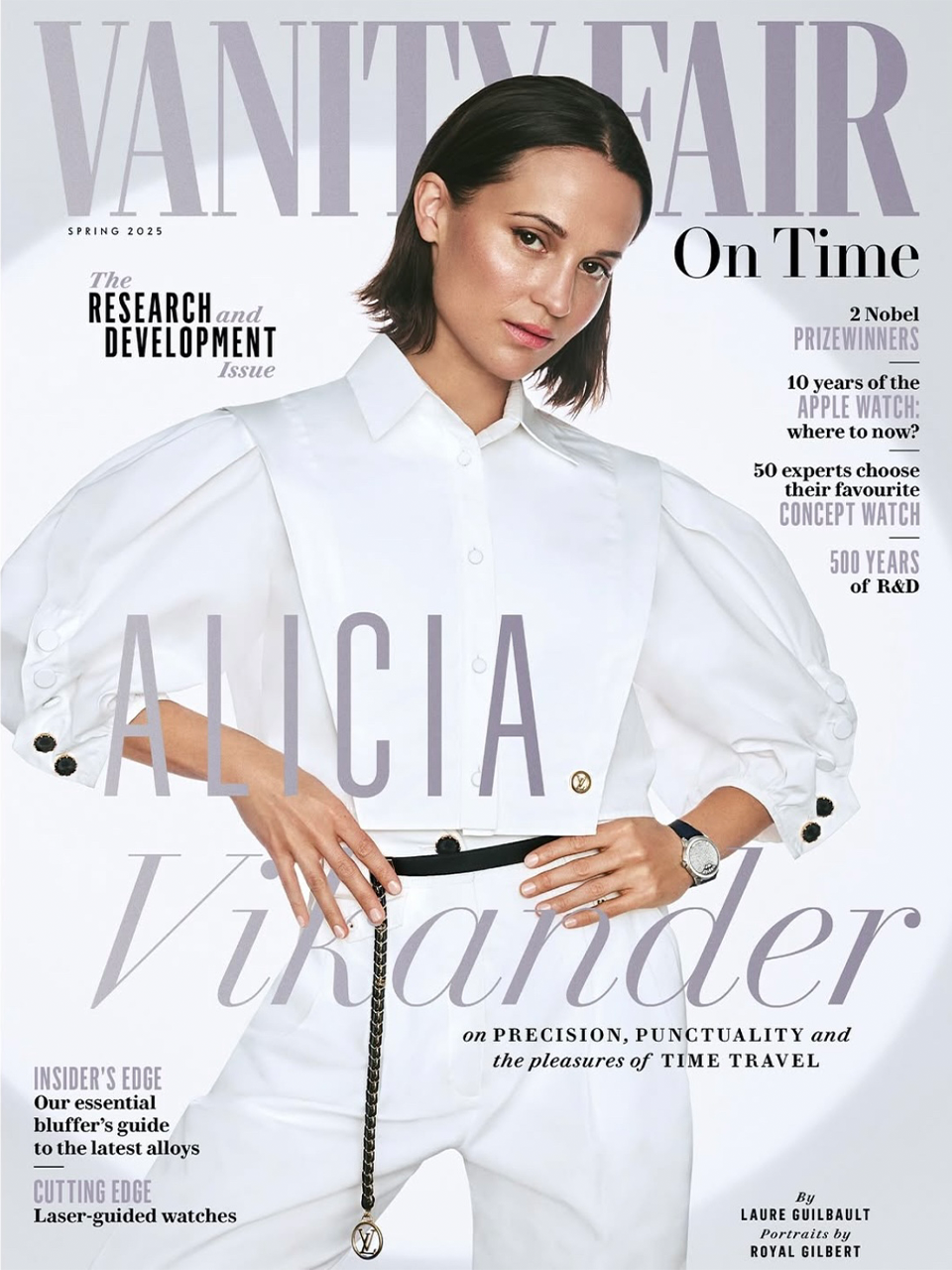 Magazine cover featuring Alicia Vikander, wearing a white outfit with puffed sleeves and black buttons, with a PM watch, posing with her hands on her hips.
