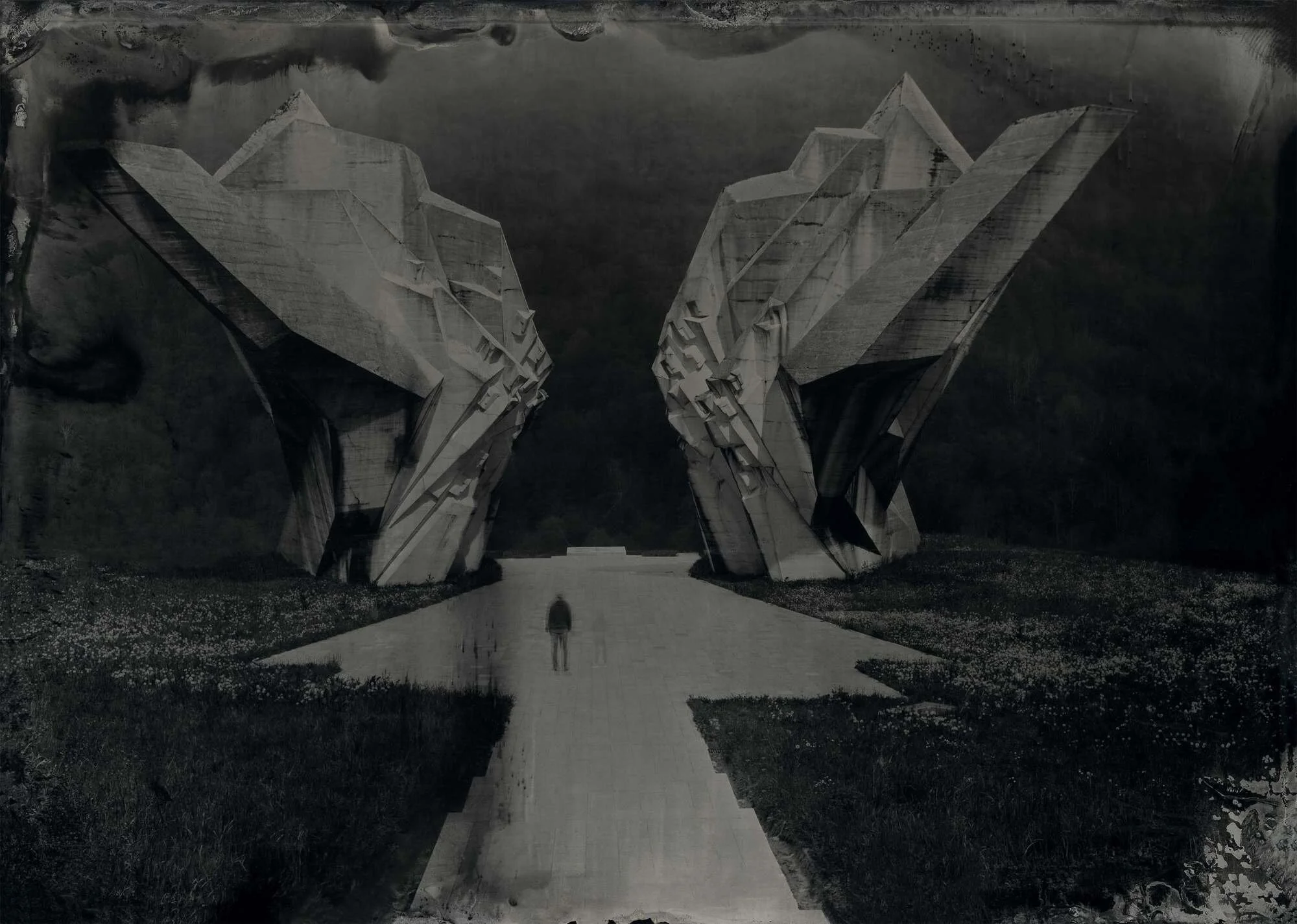 A person walking on a paved pathway towards large, modern concrete architectural structures that resemble stylized butterfly wings, set against a dark, cloudy sky.