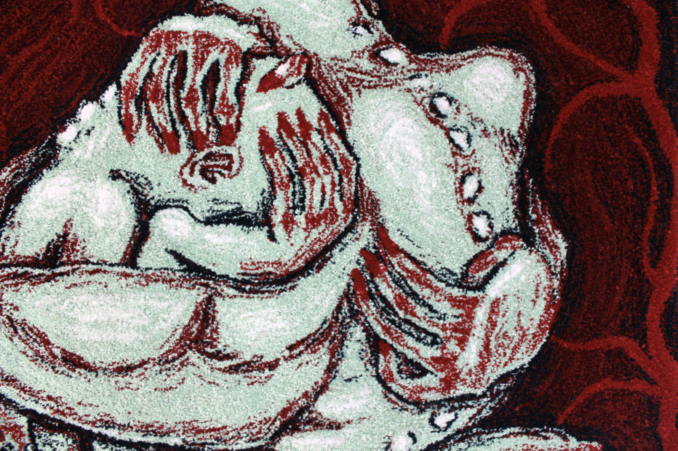 Close-up of a mosaic or image depicting two sleeping women, one with long straight hair and the other with short hair, on a red background.