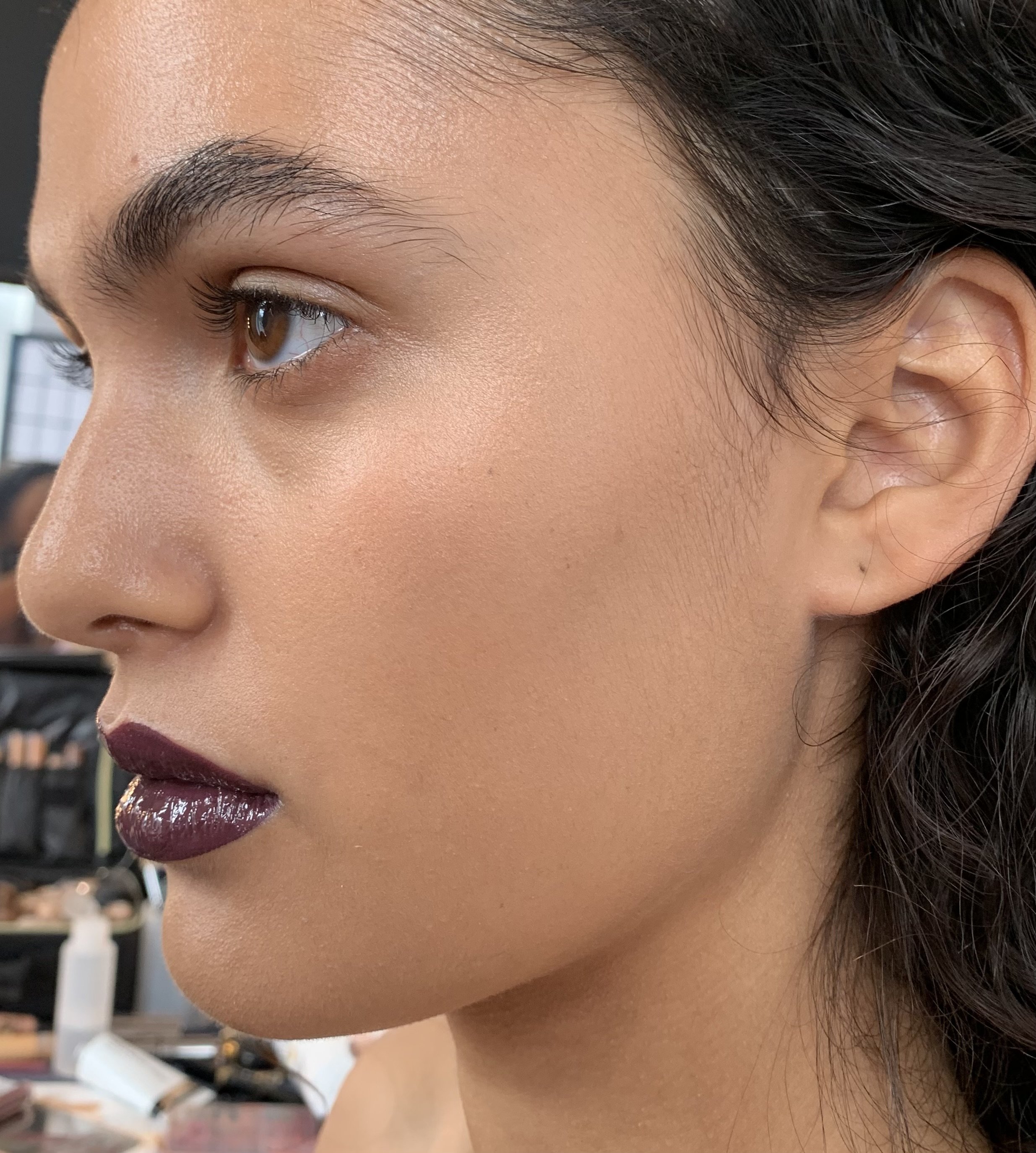 Close-up of a woman's face with makeup, including dark lipstick, in a makeup studio.