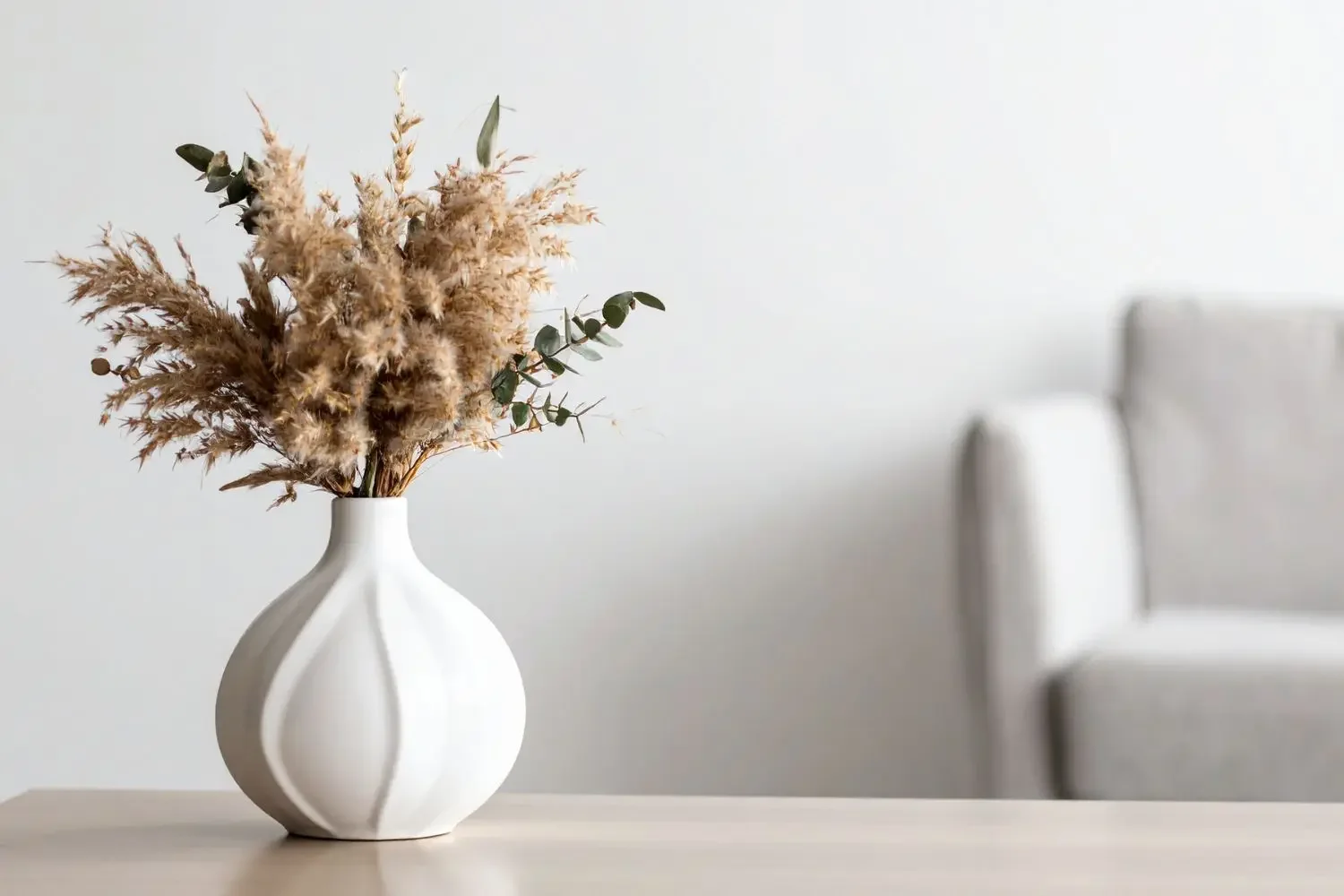 Minimalist design with grasses in a white vase, representing a reflective space for high-level life coaching and executive decision-making clarity.