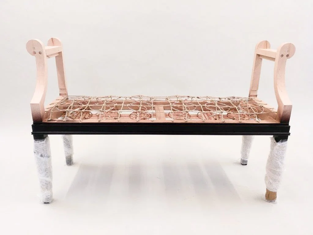 ein Kinderbettgestell ohne Matratze, meist aus Holz, mit Schutzgitter an den Seiten und Schutzstäben am Kopf- und Fußende.