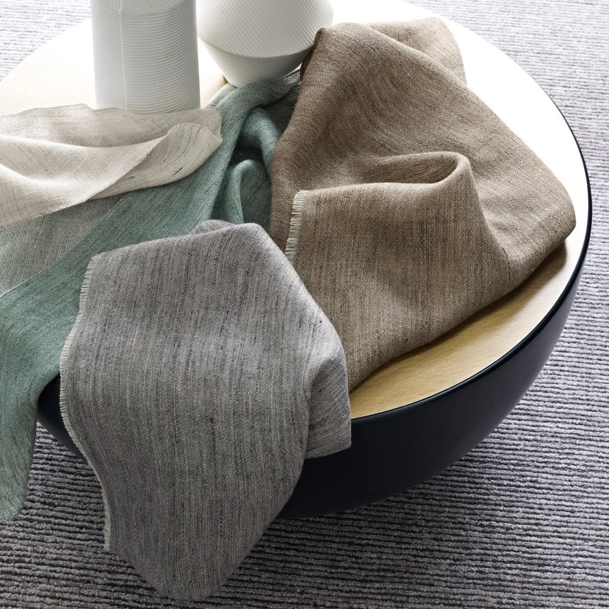 Verschiedene textile Stoffe in neutralen Tönen auf einem runden Tisch