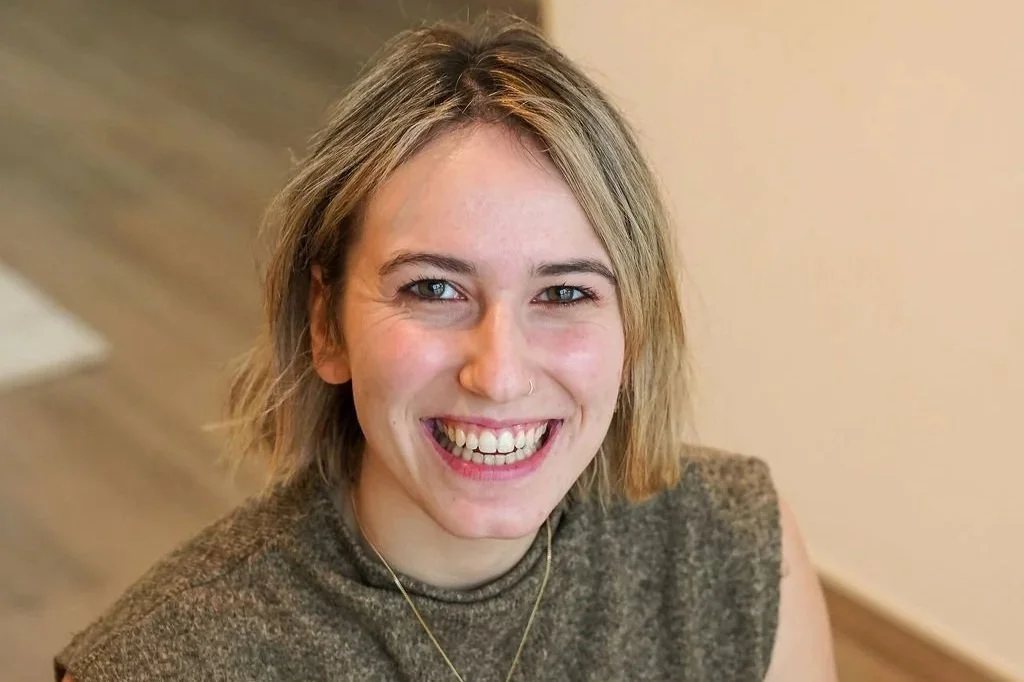 Vrouw in bruine kledij die zit op een yogamat. 