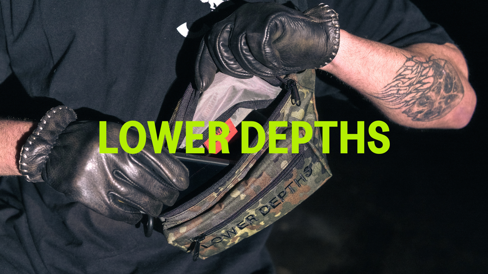 Person wearing black gloves, holding a camouflage tactical pouch with the words 'Lower Depths' overlaid in green text