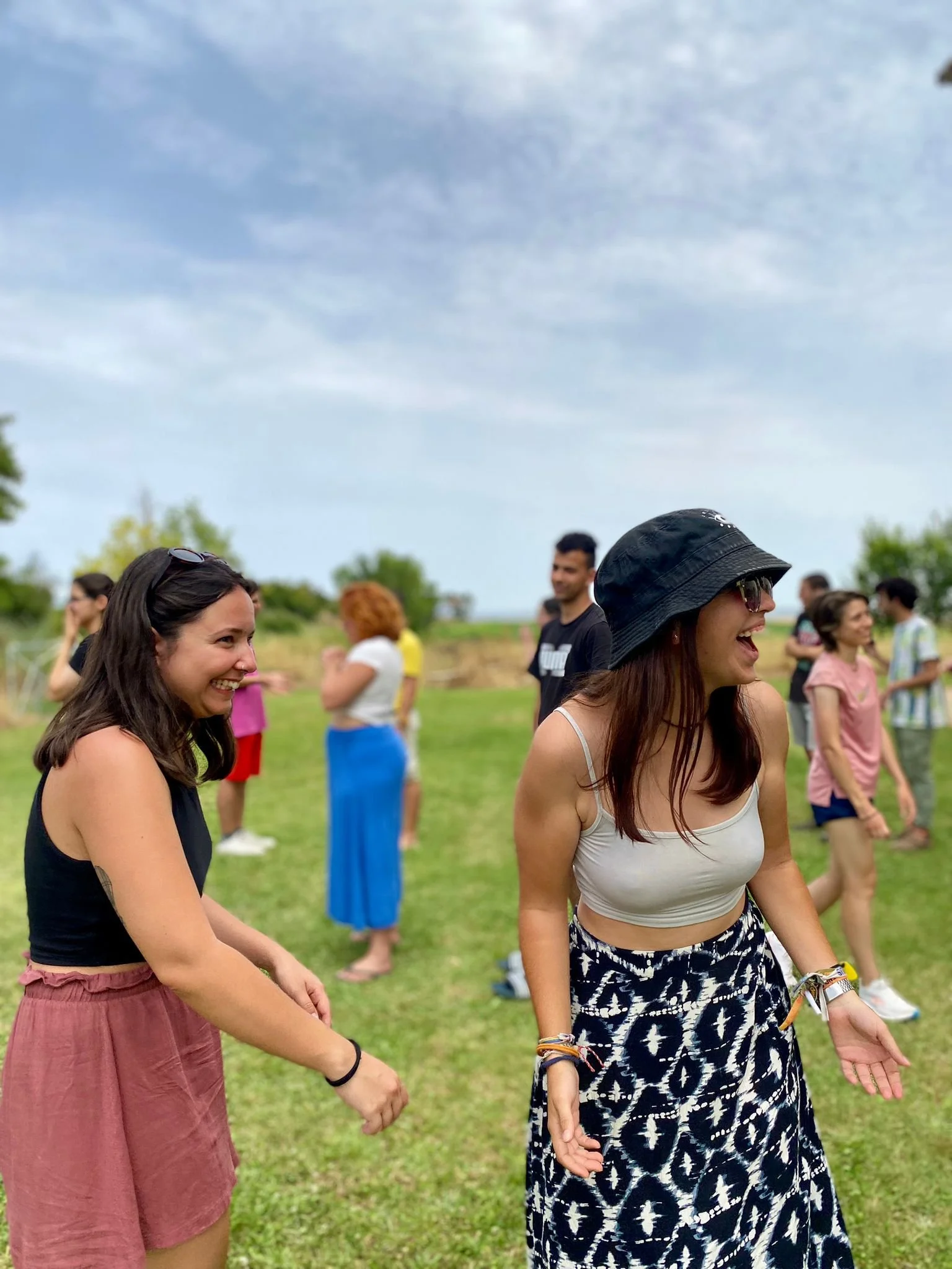 Dos chicas ríen en una actividad grupal al aire libre. 