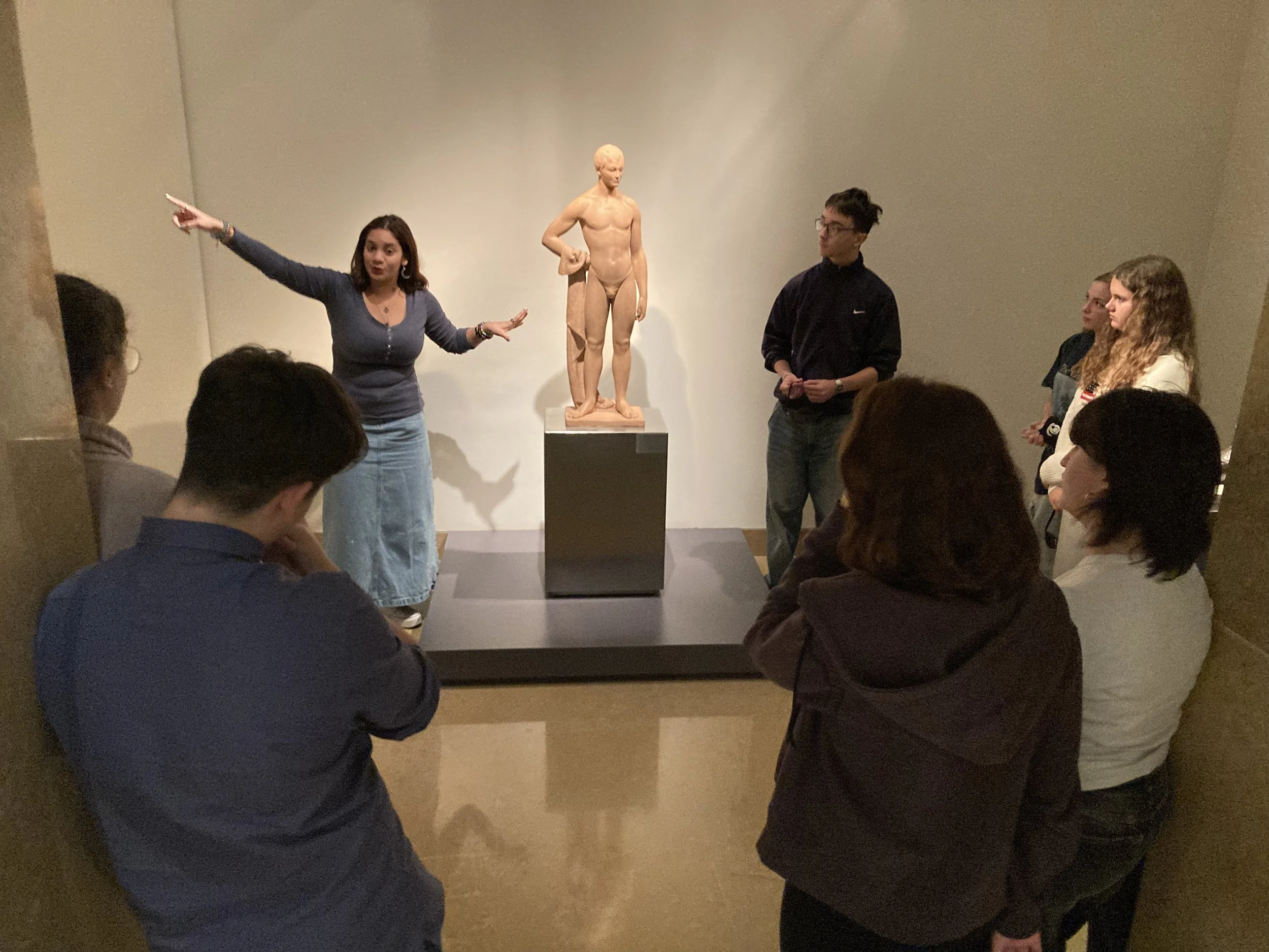 Una joven y su compañero explican una escultura al resto del equipo. 