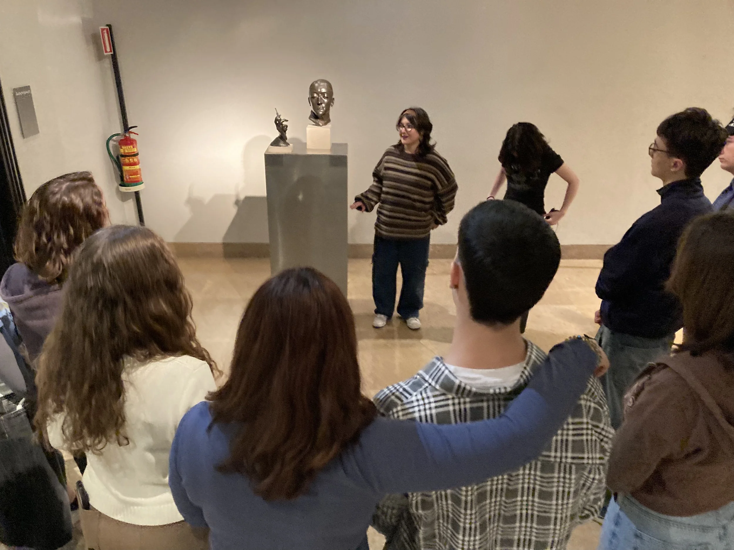 Una joven y su compañera explican una escultura al resto del equipo. 