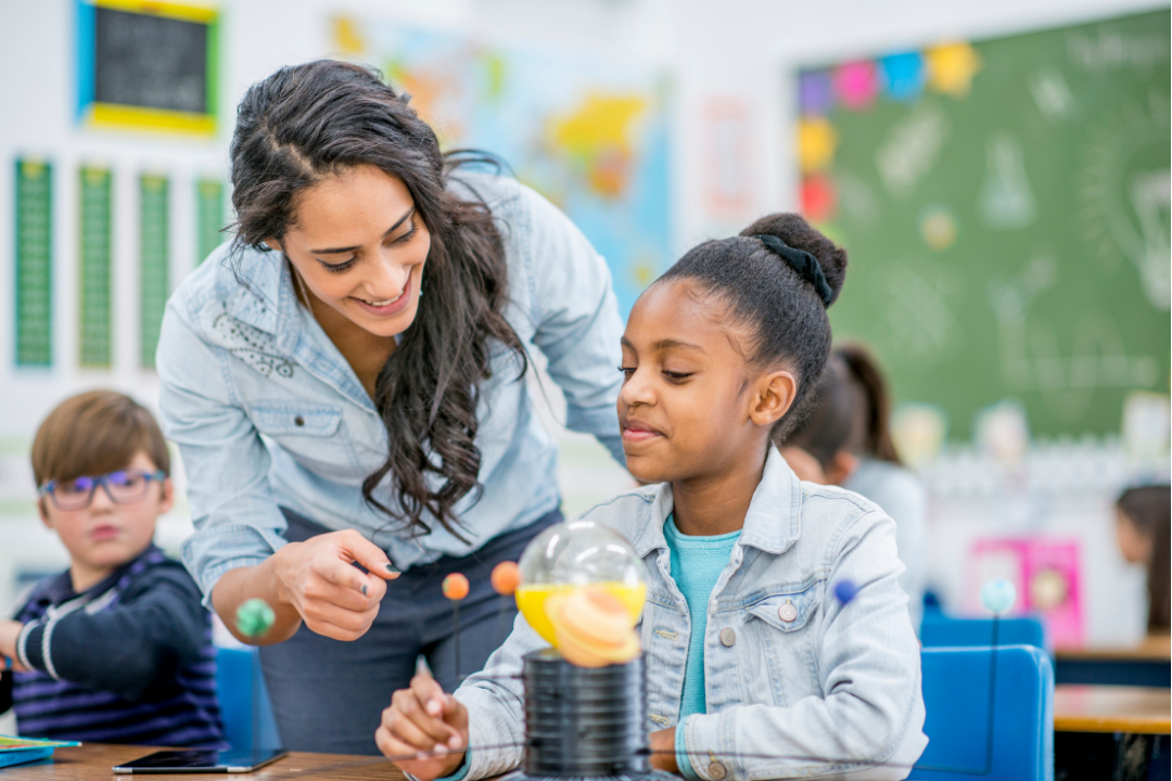 Teacher assisting a girl in a classroom.