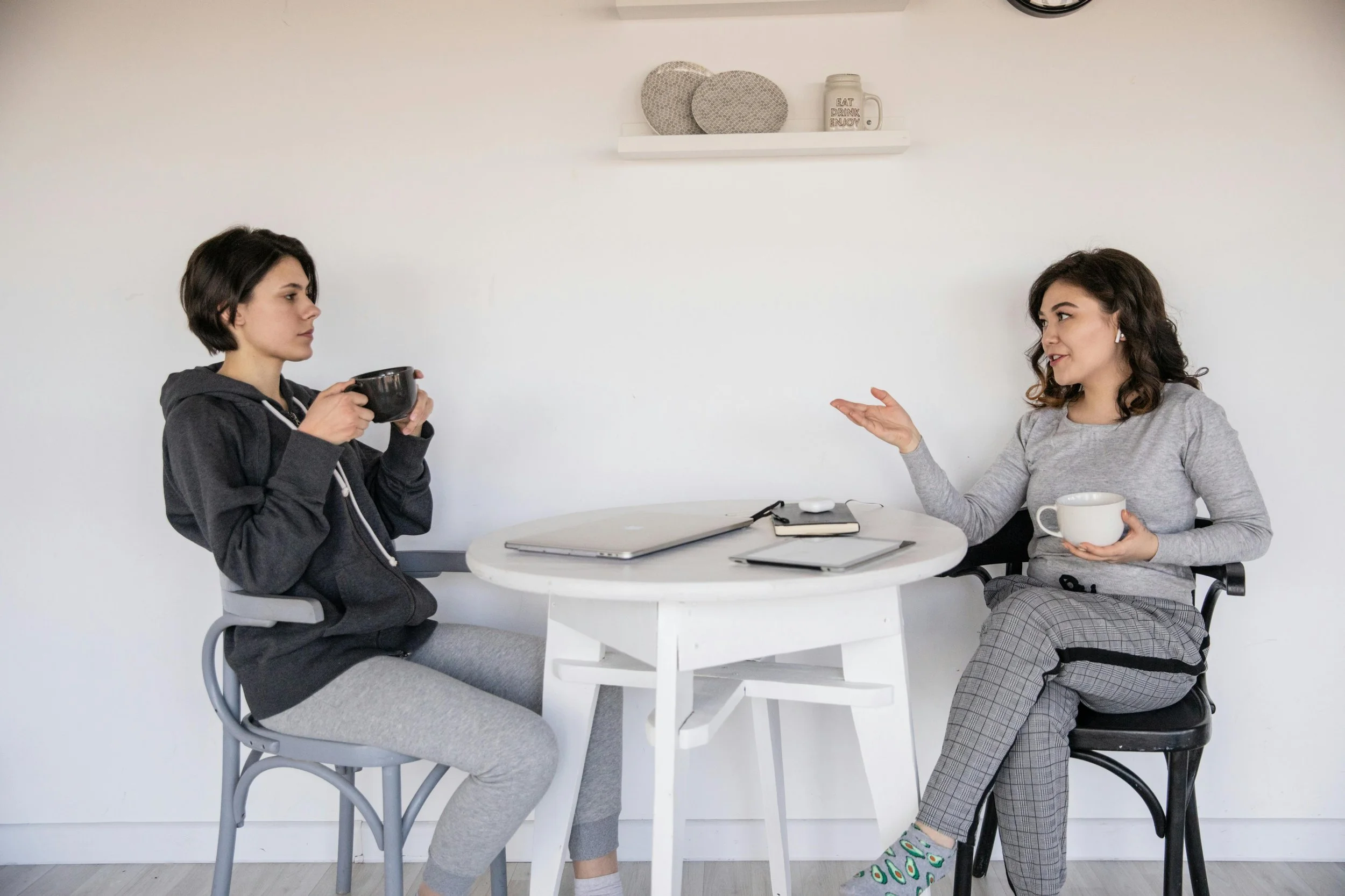 two ladies sat talking at a table drinking cups of tea