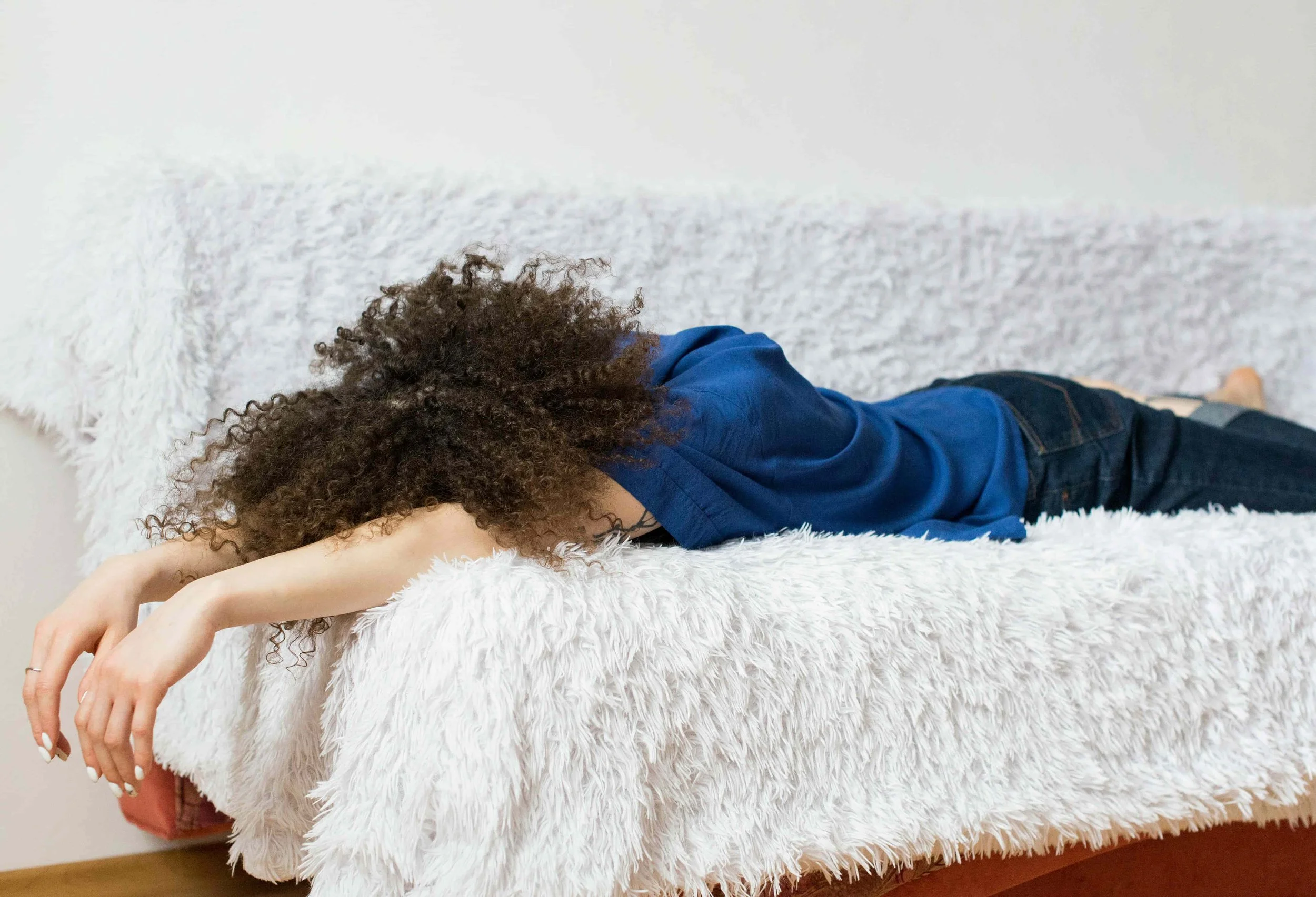 Woman resting on a couch experiencing fatigue linked to hormone and metabolic imbalance in PMOS