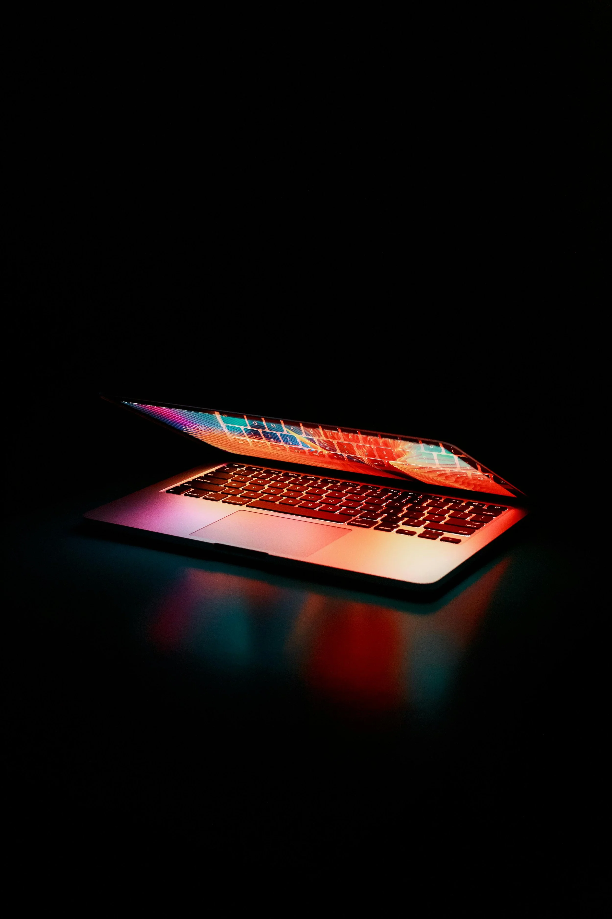 A laptop with a colorful screen glowing in a dark environment