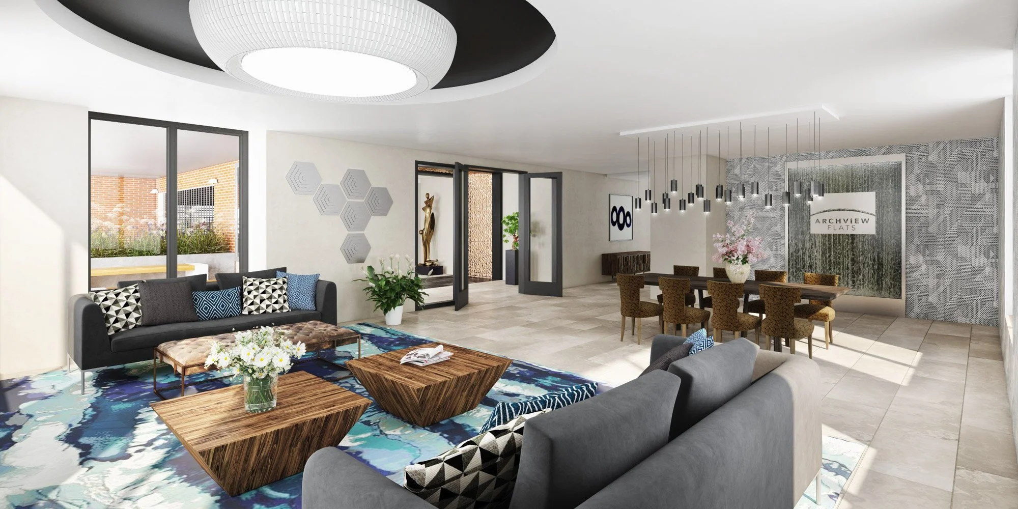 A modern lobby area with a gray sofa, patterned pillows, and wooden coffee tables on a colorful rug. There are plants, wall art, and large windows allowing natural light. The space includes a dining area with a large table, chairs, and contemporary lighting fixtures. A sign reads 'ARCHVIEW FLATS'.