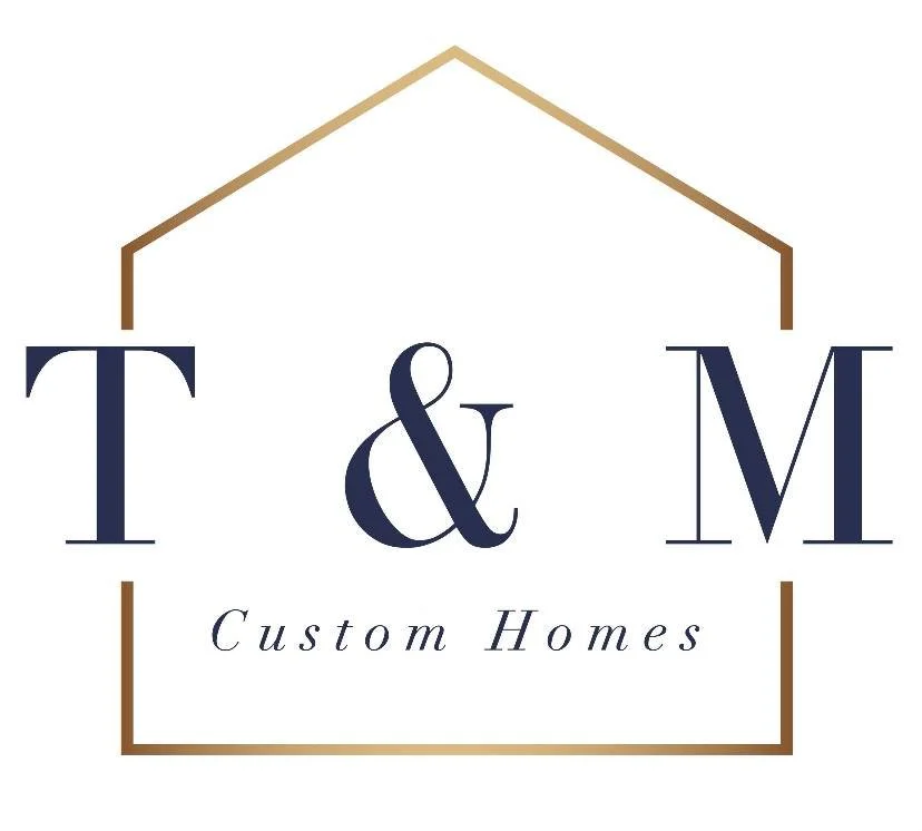Logo with the letters T & M inside a stylized house outline, with "Custom Homes" written below.