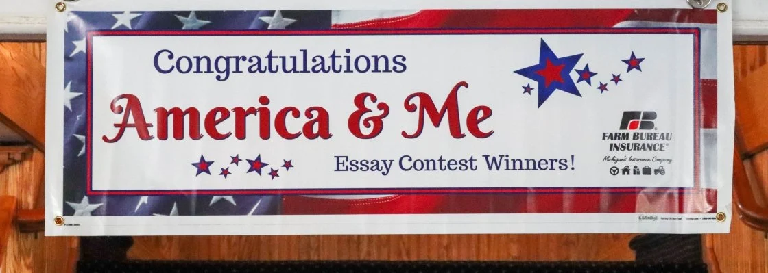 Banner celebrating winners of an essay contest titled 'America & Me' with patriotic design, stars, and logos of Farm Bureau Insurance.