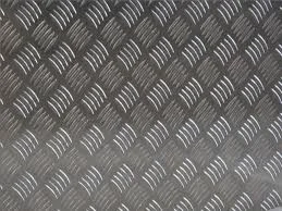 Close-up of a black textured metal surface with a raised diamond pattern