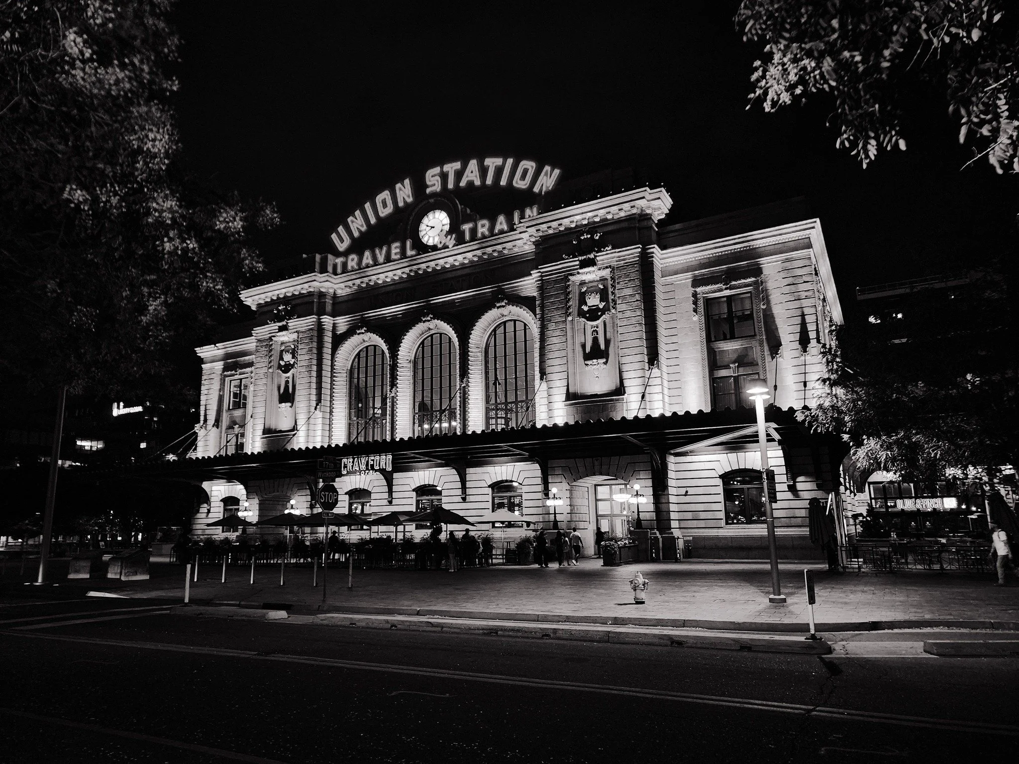 Night view of Union Station train station illuminated with lights, showing its classic architectural style and a sign that reads 'Union Station' at the top.