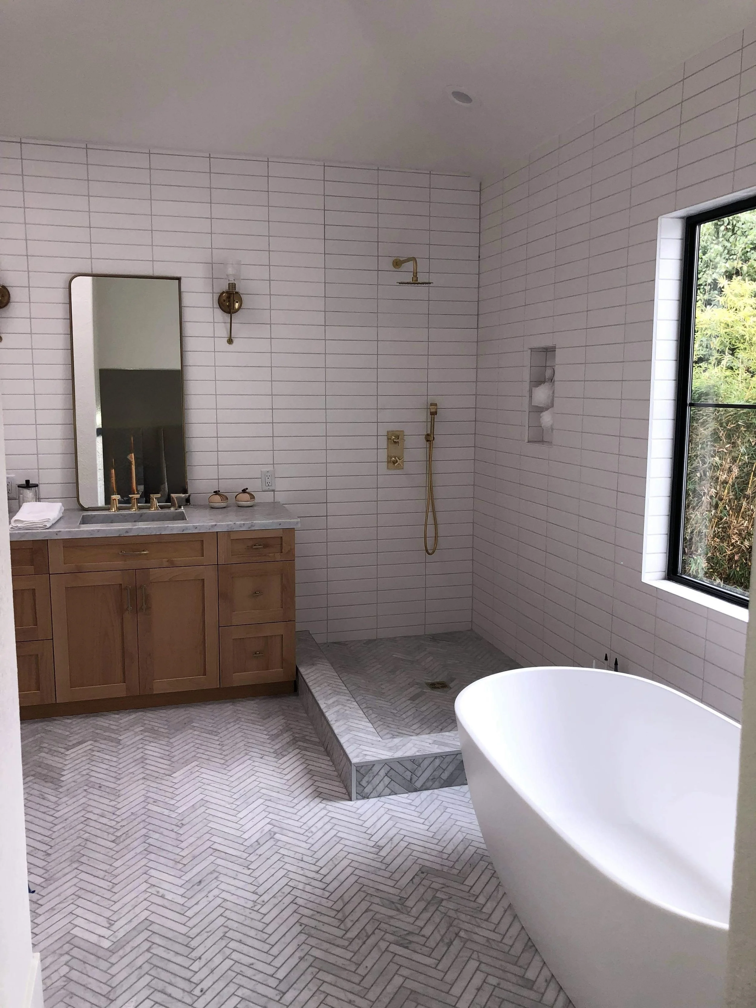 Bathroom remodel featuring modern fixtures, beautiful tile work, and gold accents by Foremost Building Solutions.