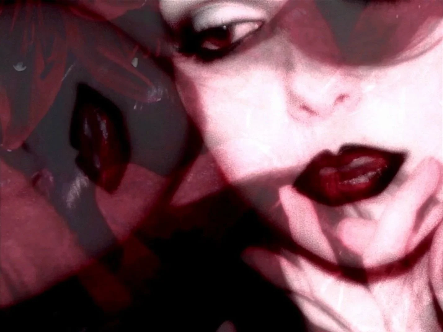 A close-up of a woman with dark lipstick, slightly parted lips, and pale skin. The image has a high contrast and artistic style.