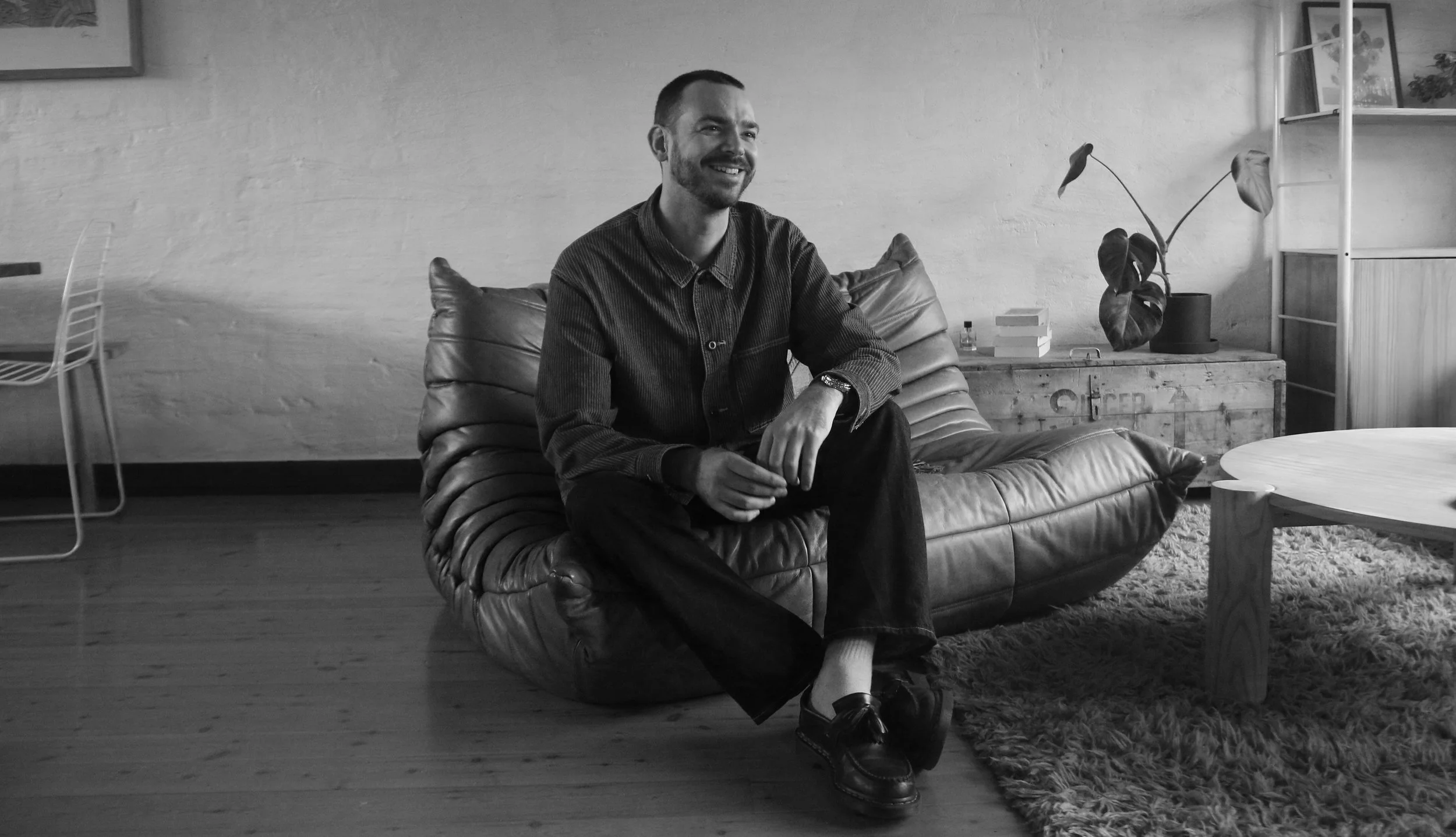 Gábor, founder of illatos, sitting on a leather couch, photographed in a warm, quiet interior.
