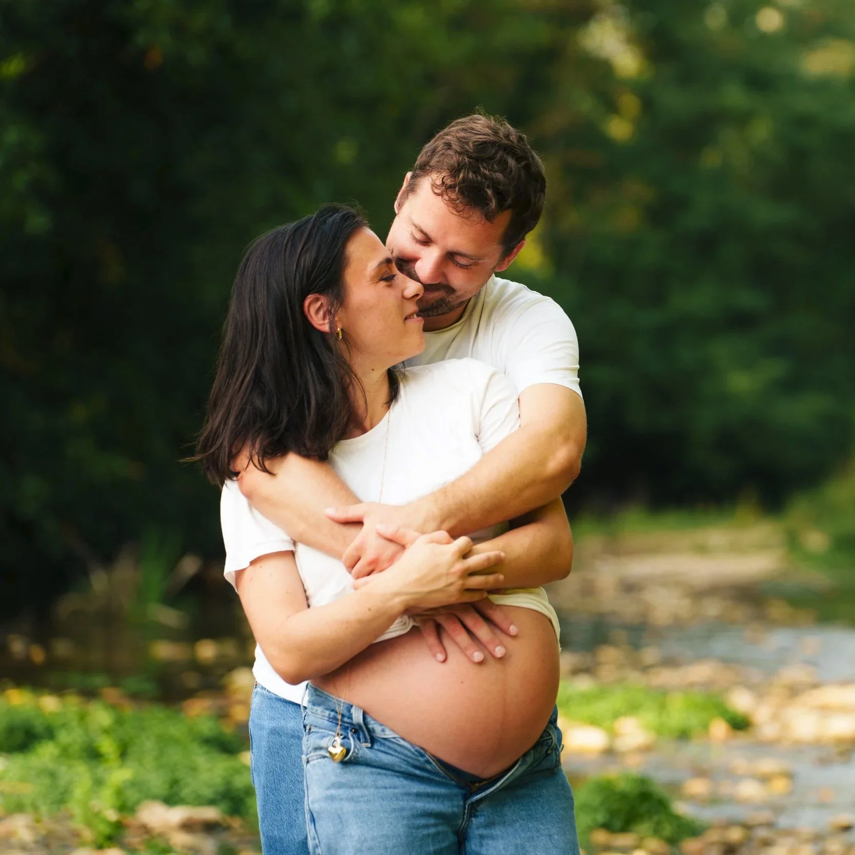 Un couple s'enlaçant, la femme est enceinte