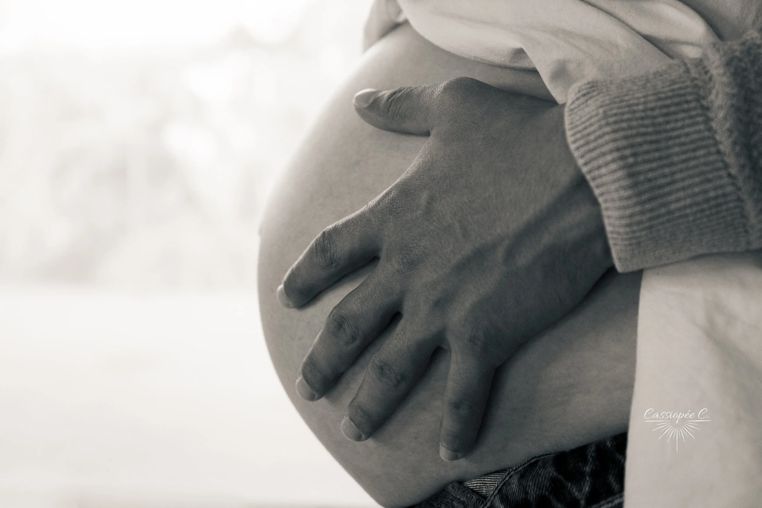 Main d'une personne reposant sur son ventre, vue en gros plan, en noir et blanc.