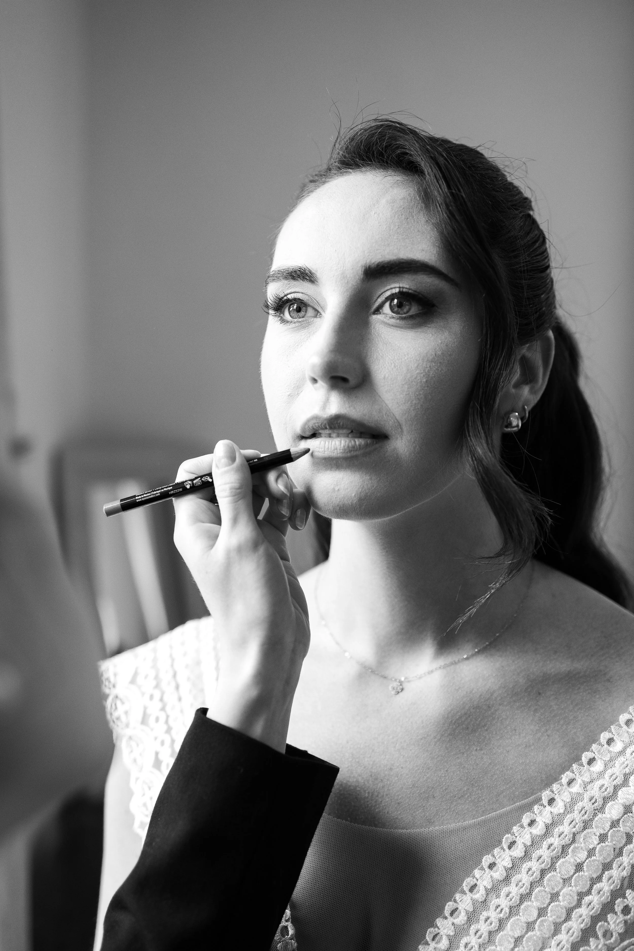 Une mariée se fait maquiller les lèvres, une photo en noir et blanc.