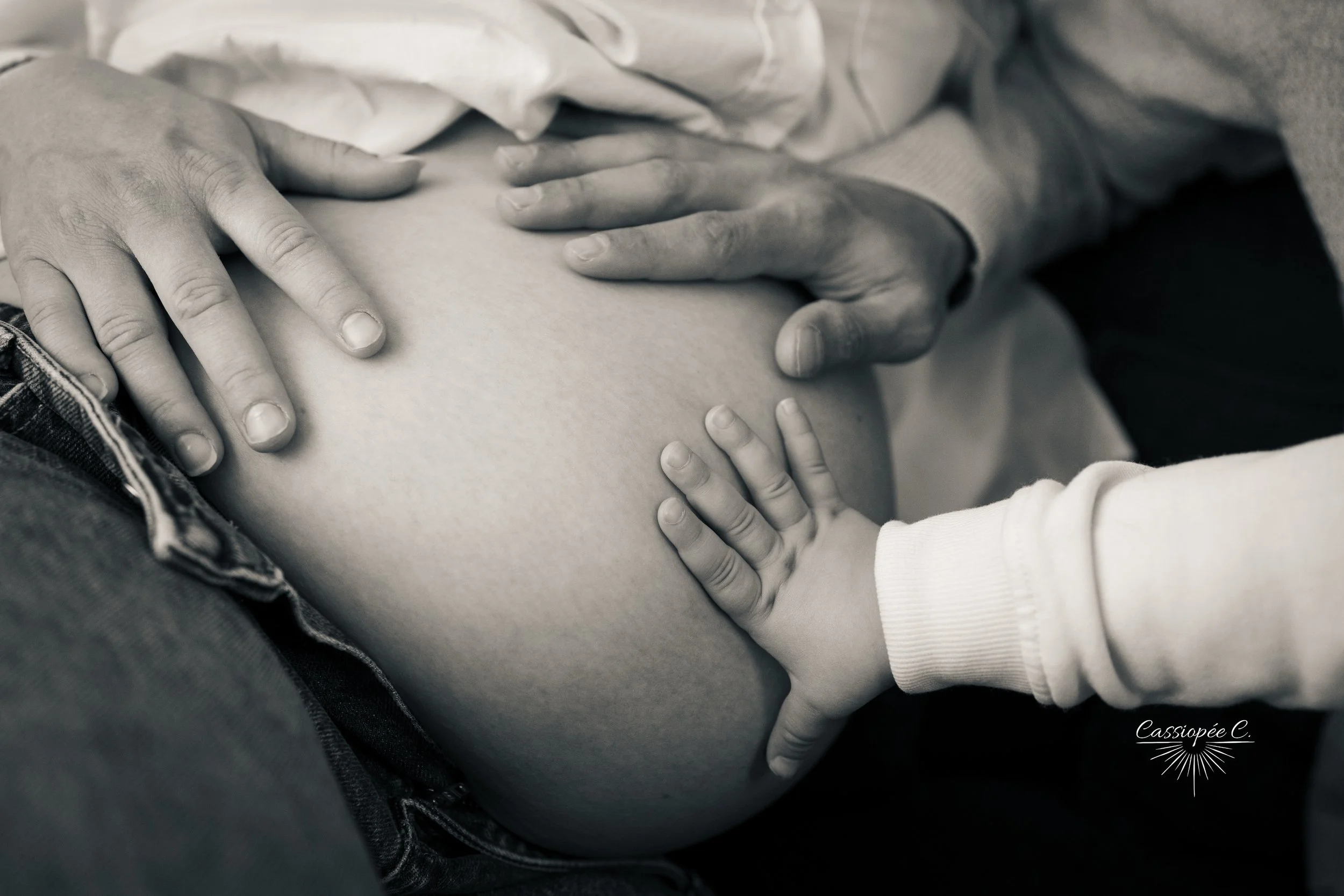 Une famille, y compris un enfant, touche le ventre d'une femme enceinte, symbolisant l'attente d'un bébé.