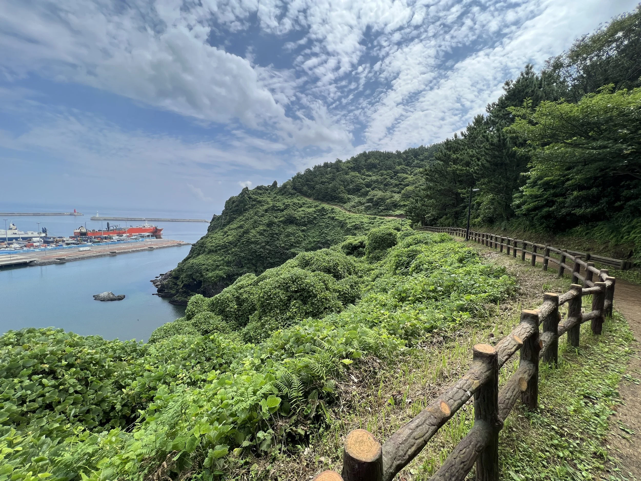 hiking trail winding around a hill with the ocean to the side.