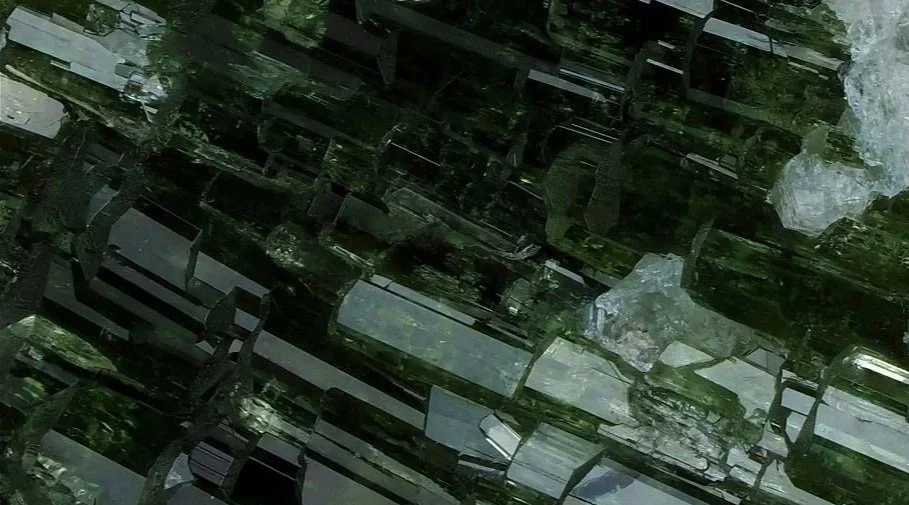 Close-up of a dark green mineral with reflective, crystalline surfaces