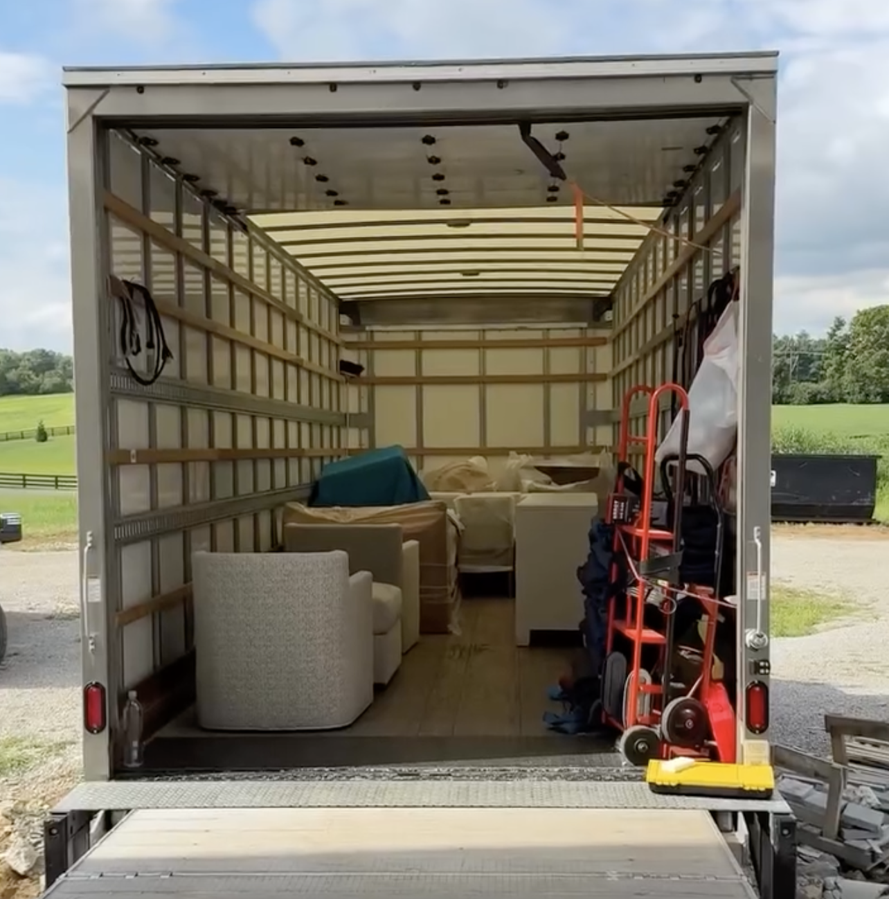 Inside of a moving truck filled with furniture and boxes, with some equipment and tools visible on the right side.