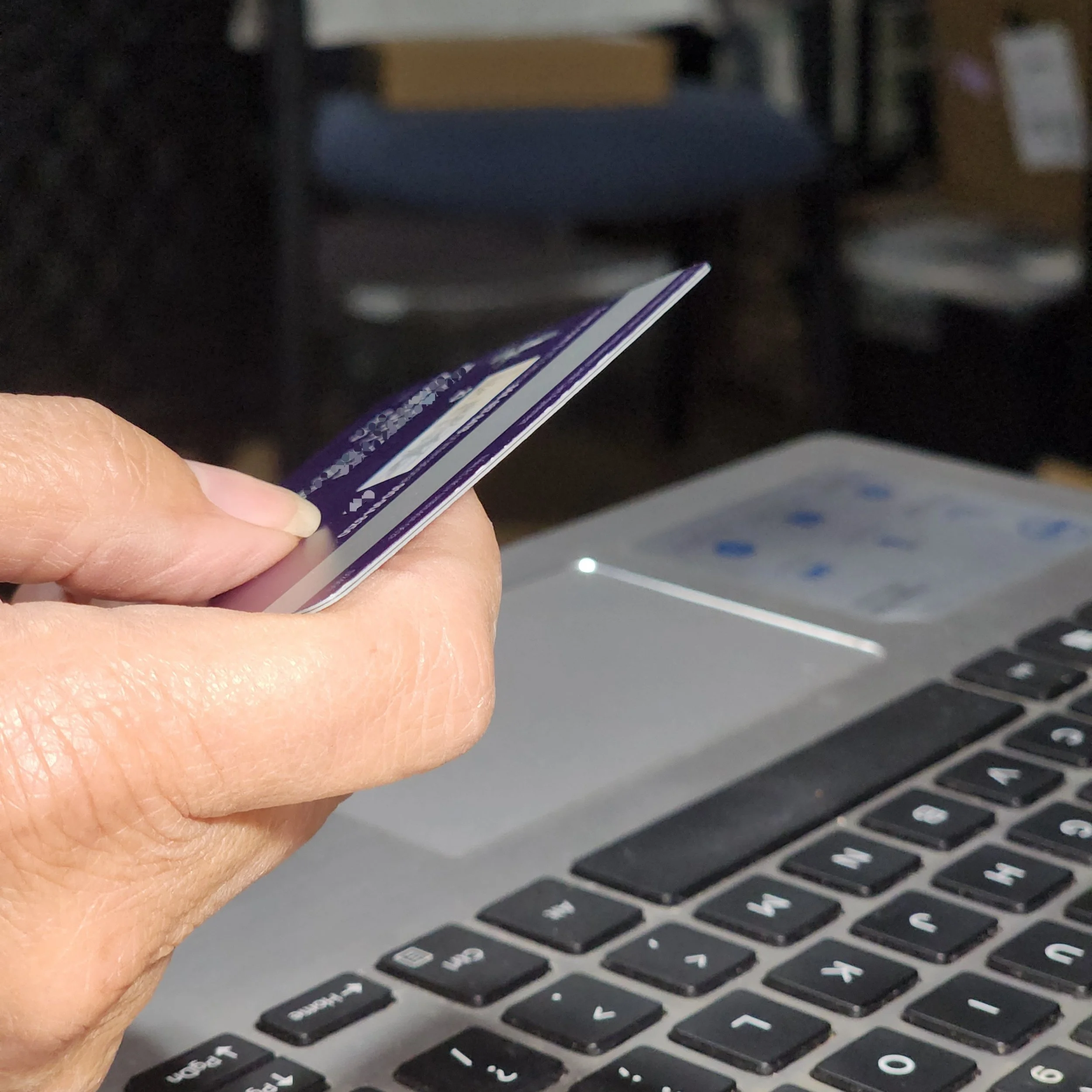 Close-up of a hand holding a credit card for online payments.