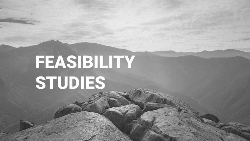 Black and white photo of mountains with large rocks in the foreground, and text that reads 'Feasibility Studies'.