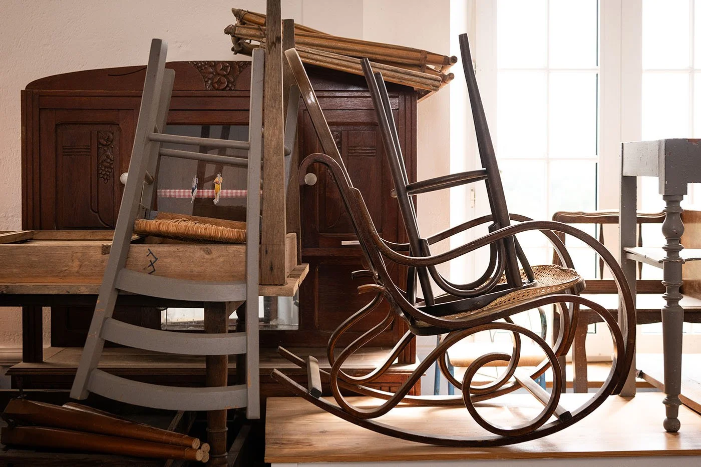 Meubles anciens en attente de restauration dans l’atelier Meliwood : chaises, rocking-chair, tables et pièces vintage à rénover.