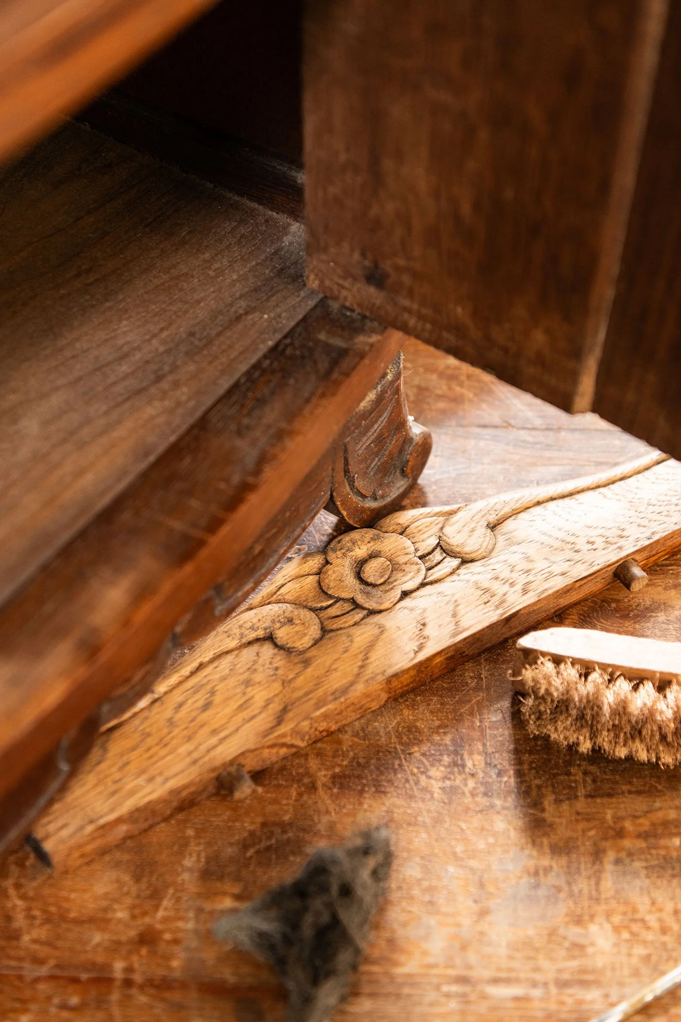Détail d’un élément en bois sculpté pendant une restauration, entouré d’outils artisanaux dans l’atelier Meliwood.