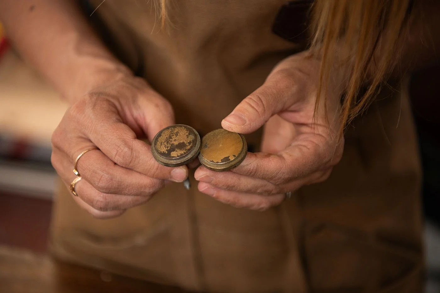 Gros plan sur des poignées anciennes tenues par Amélie lors de la restauration d’un meuble vintage dans son atelier.