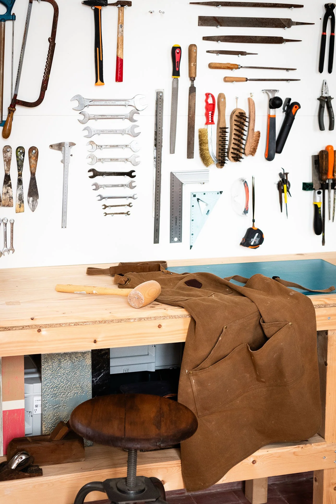 Établi de l’atelier Meliwood avec marteau, tablier de travail et outils de restauration du bois.