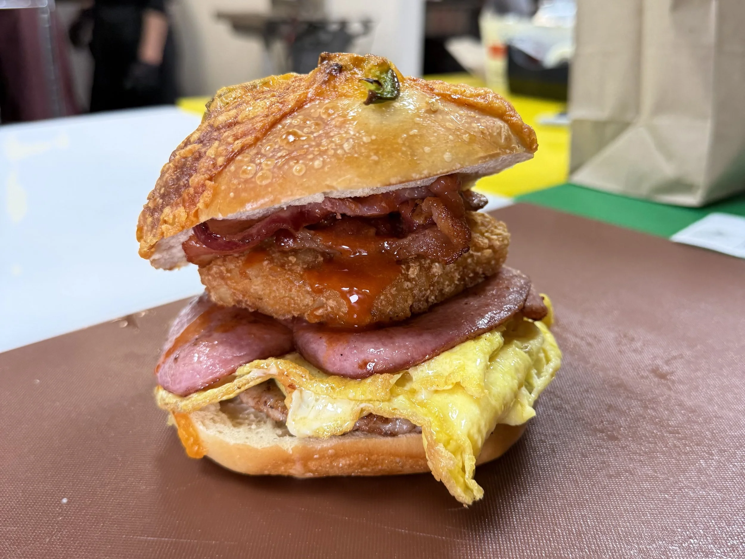 Back 2 Life breakfast sandwich layered with pastrami, ham, scrambled eggs, hash brown all in between a jalapeno cheddar bagel.