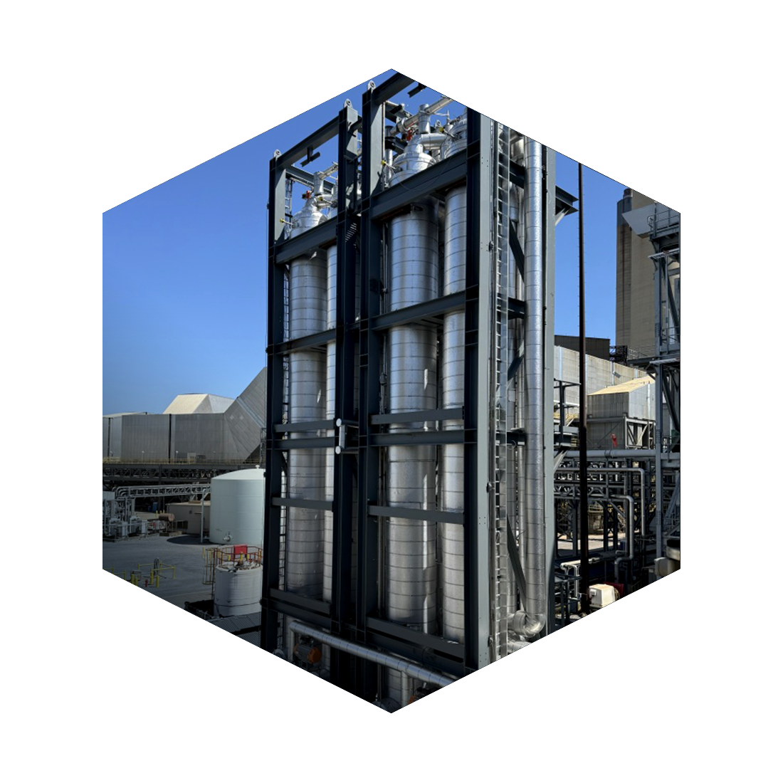 Industrial facility with large vertical silver pipes and metal framework.