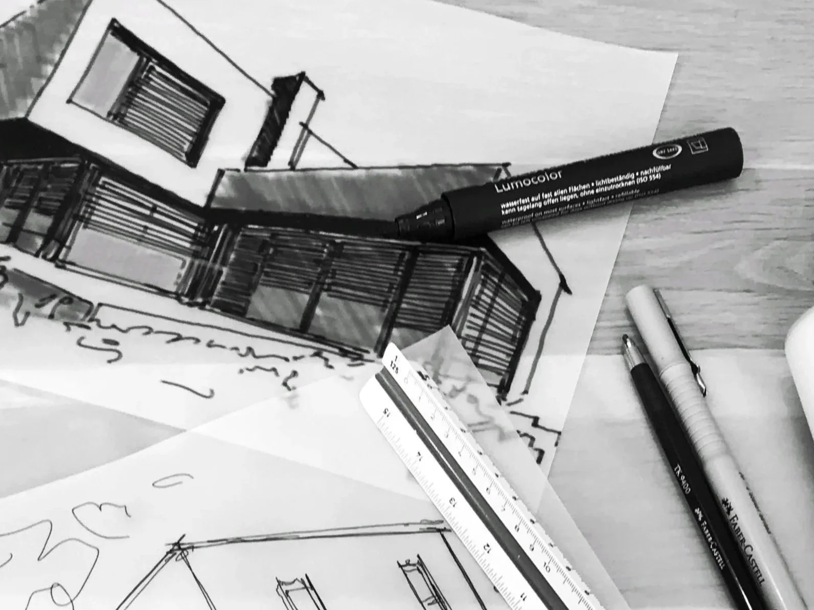 Skizzen und Zeichnungen eines Hauses, Zeichenstifte, Lineal und Marker auf einem Tisch.