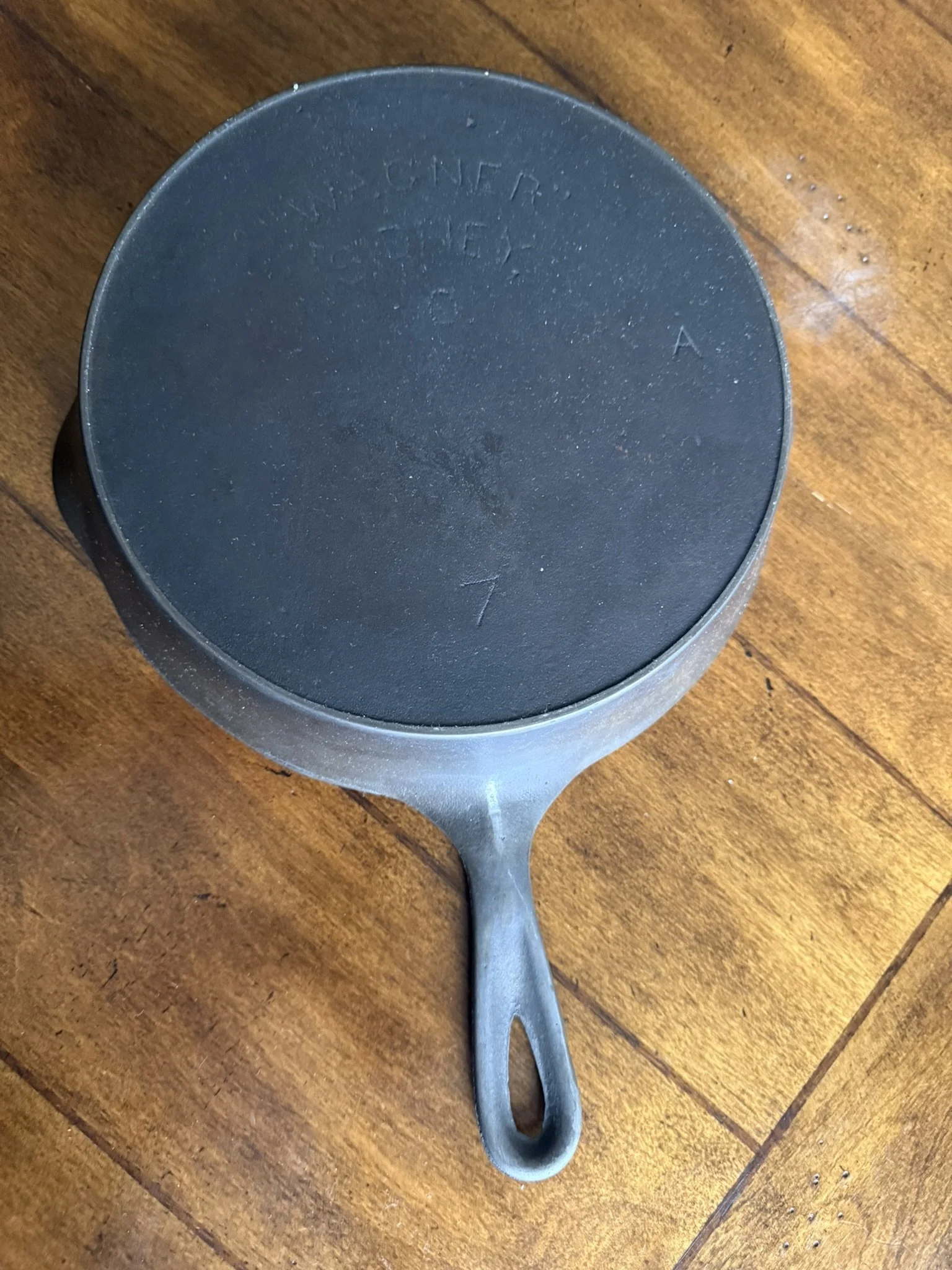 A black cast iron skillet with a long handle resting on a wooden surface.