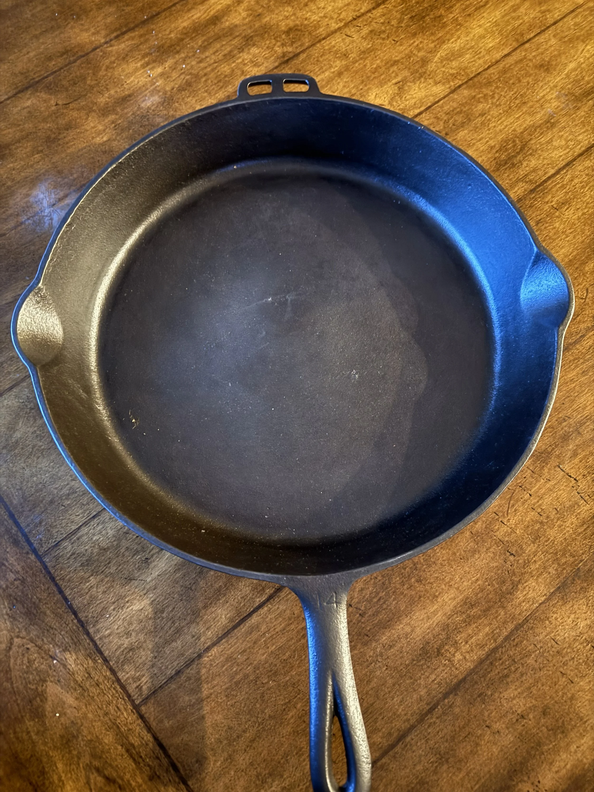 Empty black cast iron skillet on a wooden surface.